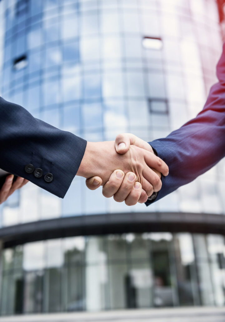 Handshakes against new business center close up